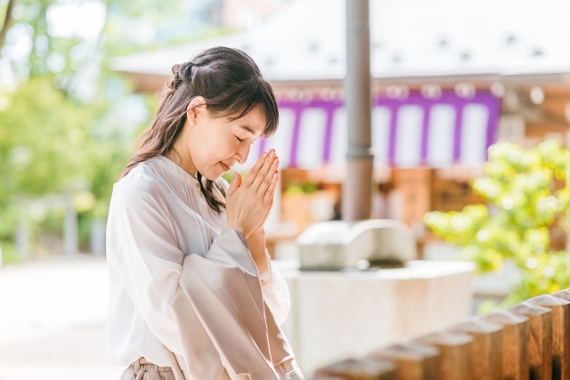 神社で手を合わせて祈願する女性のイメージ