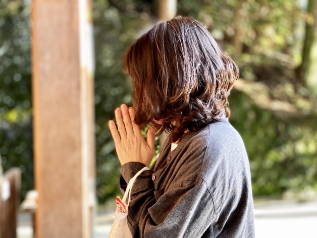 神社で手を合わせて祈る女性のイメージ